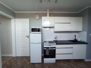 a kitchen with white cabinets and a black counter top at Apartamenty nad Zatoką - Kuźnica in Kuźnica