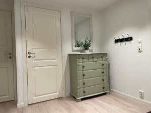 een witte kamer met een groene dressoir en een spiegel bij Leilighet med havutsikt 