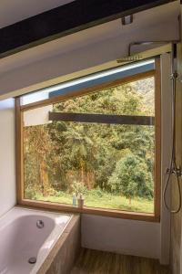 a bathroom with a window with a bath tub and a bath tub at Neblina Bird in Otavalo