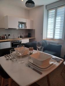 a table with plates and glasses on it in a kitchen at Mazamet - Studio neuf et moderne en centre-ville in Mazamet