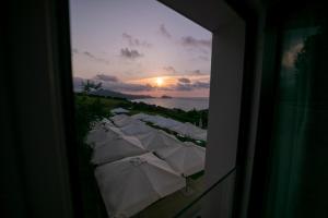 a group of white umbrellas with the sunset in the background at Hotel Boutique Berazadi Berri in Zarautz