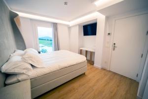 a white bedroom with a bed and a window at Hotel Boutique Berazadi Berri in Zarautz