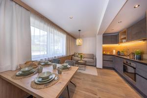 Lenni´s Apartments في بروك آن دير غروسغلوكنرشتراسه: مطبخ وغرفة معيشة مع طاولة خشبية وغرفة طعام