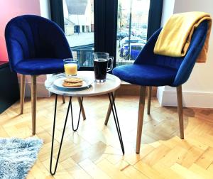 two blue chairs and a table with a plate of food at Beautiful Apartment In The Heart of Chelmsford in Chelmsford