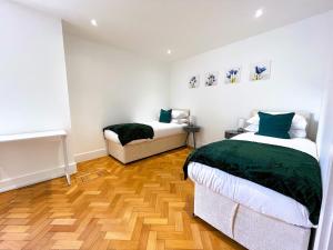 a bedroom with two beds and a wooden floor at Beautiful Apartment In The Heart of Chelmsford in Chelmsford