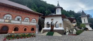 a small white church next to a brick building at La numărul 100, Nămăești in Nămăeşti