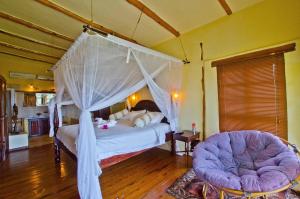 a bedroom with a canopy bed and two chairs at Casa Cabana Beach in Vilanculos
