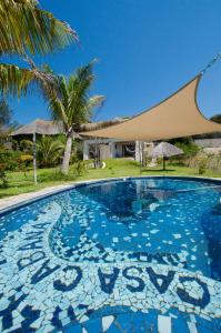 a swimming pool with a palm tree and a building at Casa Cabana Beach in Vilanculos