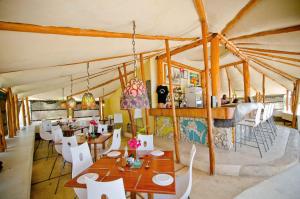 a dining room with wooden tables and white chairs at Casa Cabana Beach in Vilanculos