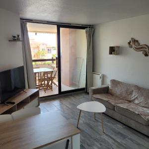 a living room with a couch and a tv and a table at Superbe appartement avec piscine in Le Barcarès