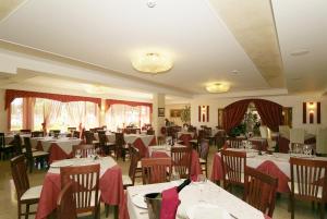 una sala da pranzo con tavoli e sedie con tovaglioli rossi di Fashion Hotel a Valmontone