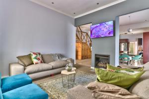 a living room with a couch and a tv on a wall at SASHORES- 6 on Ellis in Cape Town