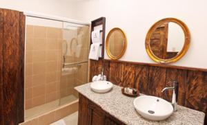 a bathroom with two sinks and a shower and mirrors at Hacienda Hostería Dos Chorreras in Cuenca