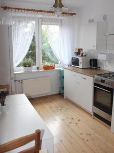 a kitchen with white cabinets and a table and a window at Galicja Apartamenty in Rzeszów