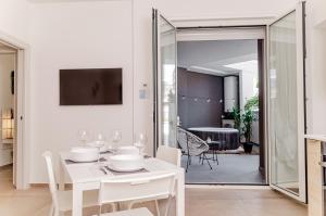 a white dining room with a table and a mirror at [ApuliaLux] Design Apartment - Relax, SPA e Free Parking in Bari