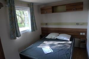 a bedroom with a bed with a mirror and a window at Camping de Pont Calleck in Inguiniel