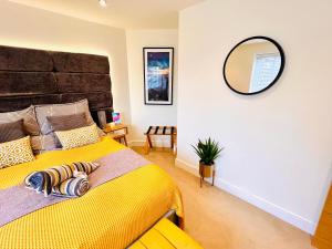 a bedroom with a yellow bed and a mirror at The Duplex with Air Conditioning & Private Deck Area in Margate