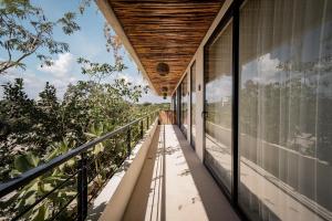 a balcony of a house with a view of trees at Unique & Stylish Apartment With Lovely Decked Terrace & Awesome Floating Pool In Tulum in Tulum