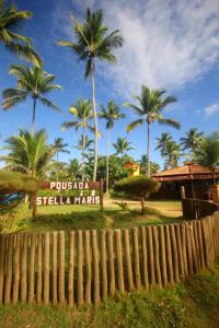 uma placa na entrada de um resort com palmeiras em POUSADA STELLA MARIS em Canavieiras