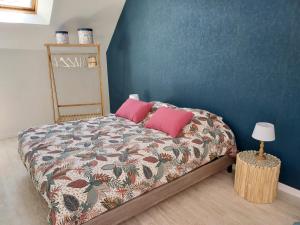a bedroom with a bed with two pink pillows at Sous murs, petite maison de ville au charme authentique in Auxerre