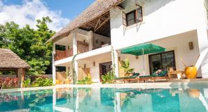a villa with a swimming pool in front of a house at Daima Villas in Jambiani