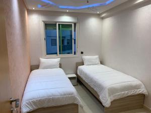 two beds in a room with a blue ceiling at Résidence Le joyau de la mer Plage Des Nations in Sidi Bouqnadel