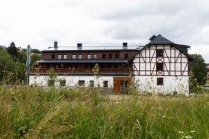 a white building with a black roof in a field at Wellness Apartmán Pila Kvilda in Kvilda