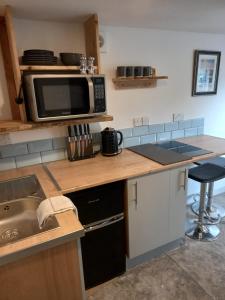 a kitchen with a counter with a microwave and a sink at Wee Shot in Tain