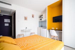 een slaapkamer met een geel bed en een keuken bij Joli studio proche gare et centre ville in Lourdes