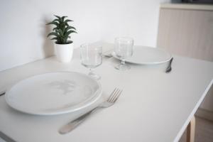een witte tafel met twee borden en glazen erop bij Joli studio proche gare et centre ville in Lourdes