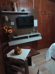uma sala de estar com uma televisão e uma mesa em Rancho da Raposa em Campos do Jordão