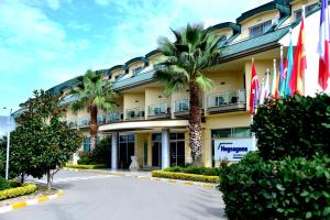 a hotel with palm trees and flags in front of it at Hotel Hegsagone Marine Asia in Gebze