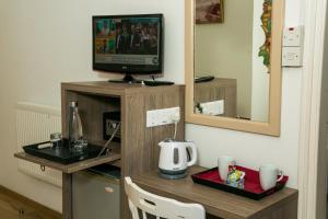 a room with a tv on a wooden stand with a table at Fitosinn Hotel in Paphos