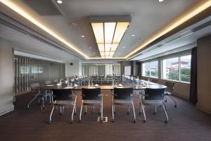 Ramada Hotel & Suites by Wyndham Izmir Kemalpasa في Kemalpaşa: قاعة اجتماعات كبيرة مع طاولة وكراسي طويلة