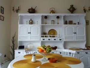 una cocina con armarios blancos y una mesa con un bol de fruta en Wagner Apartman Tata, en Tata