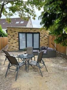 a patio with a table and chairs and a couch at Modern Studio with parking in private garden in Theydon Bois