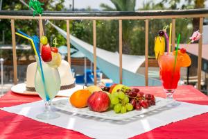 a table with a plate of fruit and two cocktails at Fitosinn Hotel in Paphos