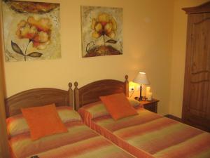 Ballobar的住宿－Casa La Mercedes，卧室内的两张床,墙上挂有绘画作品
