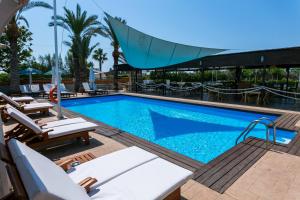 a pool at a hotel with lounge chairs and a swimming pool at Fitosinn Hotel in Paphos