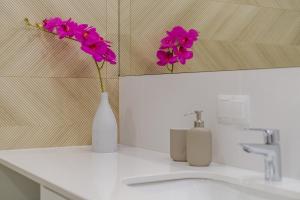 two pink flowers in a white vase on a sink at Apartamenty i pokoje Krupówki 16, Na Szczytach in Zakopane