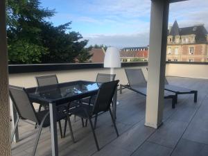 eine Terrasse mit einem Tisch und Stühlen auf dem Balkon in der Unterkunft Aux Grès des Vagues in Lion-sur-Mer