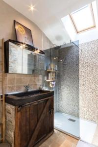uma casa de banho com um chuveiro, um lavatório e uma porta de vidro em Gite Kerlaguito em Pontchâteau