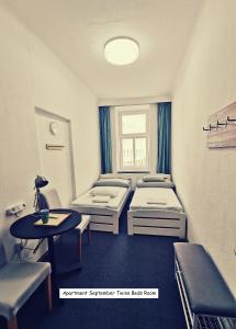 7brunnen Hostel & Guest House في فيينا: غرفة مستشفى بسريرين وطاولة