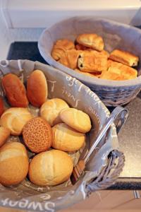 a table with two baskets of bread and a bowl of pastries at Hotel Uilenspiegel in Nieuwpoort