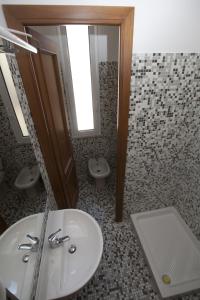 a bathroom with a sink and two toilets and a mirror at Italy Inn in Genoa