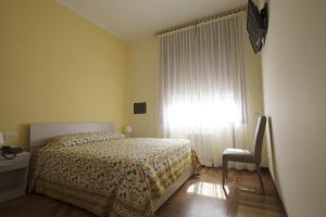 1 dormitorio con cama, ventana y silla en Italy Inn, en Génova