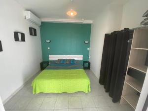 - une chambre avec un lit et une couverture verte dans l'établissement akate, à Les Trois-Îlets