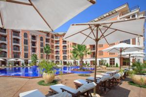 a hotel with chairs and umbrellas and a swimming pool at Cascadas Ravda in Ravda