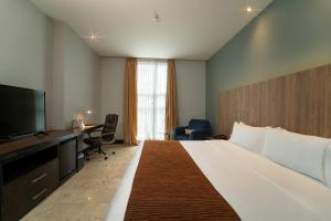 Habitación de hotel con cama grande y escritorio. en GHL Hotel Barranquilla en Barranquilla