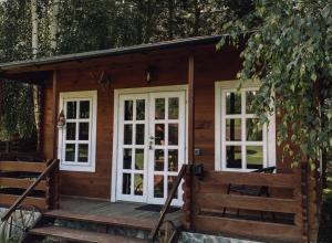 a log cabin with white windows and a porch at Laumių Nameliai in Anykščiai